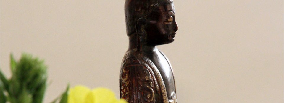 Buddha statue. Photo of a small Buddha statue beside a vase of yellow flowers